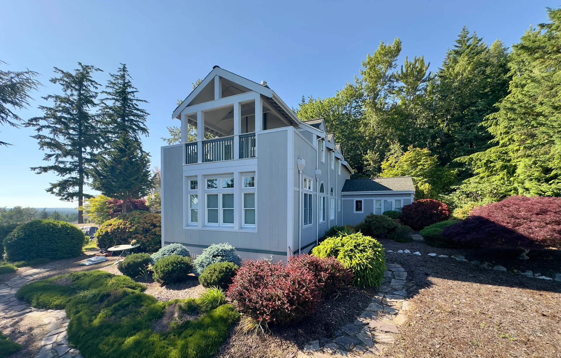 Two-story custom home on King Mountain with a gabled covered balcony, viewed from the landscaped front yard.