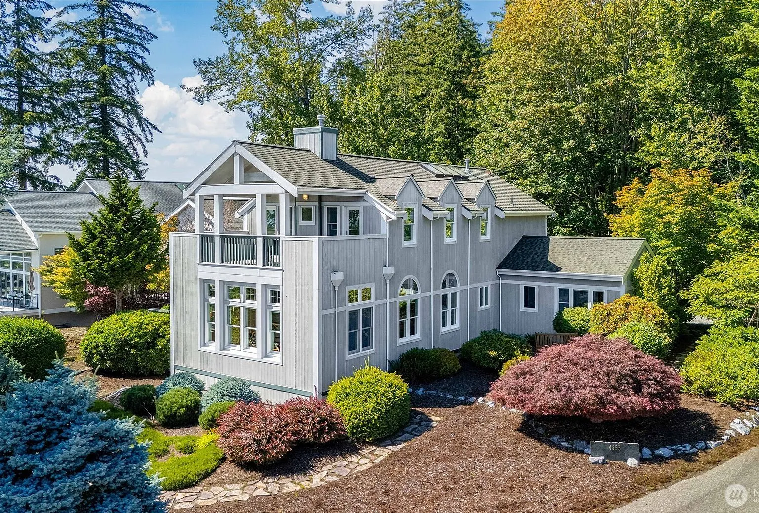 Two-story custom home on King Mountain with a gabled covered balcony, viewed from the landscaped front yard.