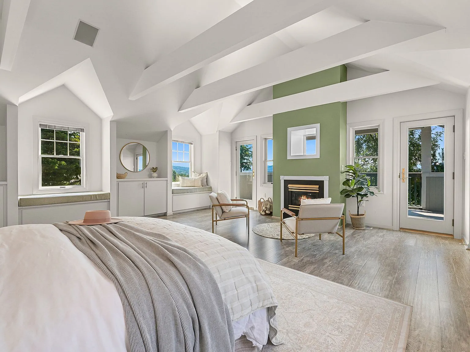 Bedroom with a stone fireplace, built-in window seat, and French doors opening to a private deck.